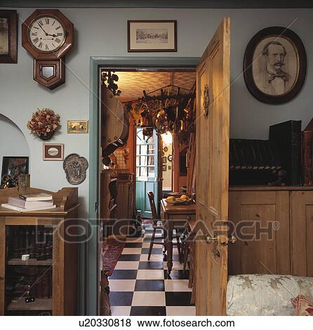 Clock on wall above open pine door with view of black+white checked flooring in traditional kitchen View Large Photo Image Stock Photo - Clock on wall above open pine door with view of black+white checked flooring in traditional kitchen . Fotosearch