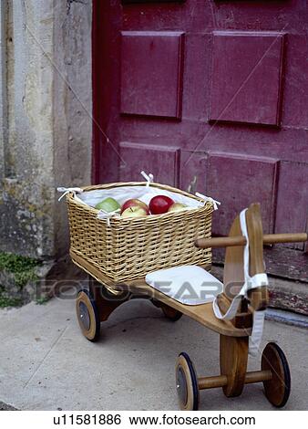 Stock Photograph - Close-up of basket of apples on child's wooden tricycle. Fotosearch