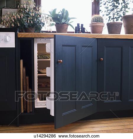 Stock Photograph - Close-up of blue cupboard door open to reveal built-in refrigerator. Fotosearch