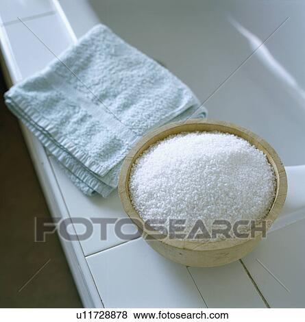 Stock Photo - Close-up of blue towel and bath salts in wooden bowl on the side of the bath. Fotosearch