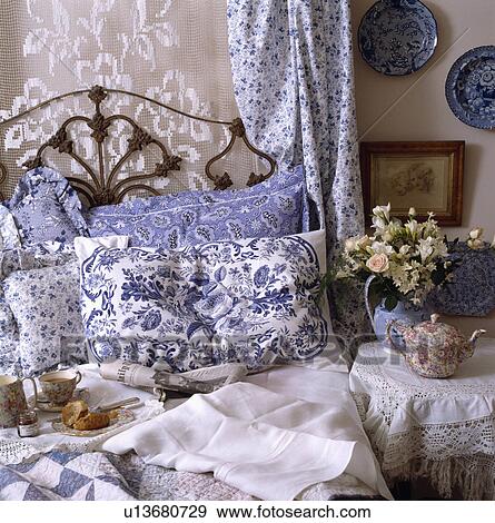 Close-up of blue+white pillows on wrought iron bed with lace drapes behind bed and Chintz teapot on bedside table View Large Photo Image Stock Photo - Close-up of blue+white pillows on wrought iron bed with lace drapes behind bed and Chintz teapot on bedside table. Fotosearch