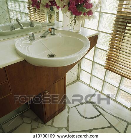 Close-up of circular white basin in white-topped wood vanity unit beside glass brick wall in modern bathroom View Large Photo Image Stock Photo - Close-up of circular white basin in white-topped wood vanity unit beside glass brick wall in modern bathroom. Fotosearch