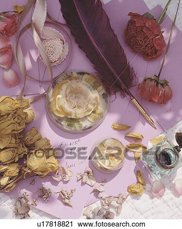 Stock Image - Close-up of dried roses and paperweights with quill pen. Fotosearch