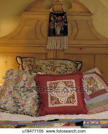 Close-up of floral and patchwork cushions on bed with pine headboard View Large Photo Image Stock Photography - Close-up of floral and patchwork cushions on bed with pine headboard. Fotosearch