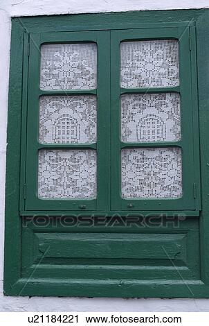 Stock Image - Close up of green window with lace curtain. Fotosearch