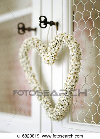 Stock Photo - Close-up of hear-shaped dried flower decoration hanging from key on cupboard door. Fotosearch