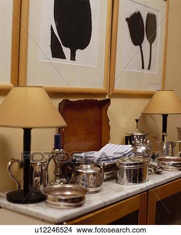 Close-up of lamps and silver jugs and dishes on marble topped sideboard below black+white pictures View Large Photo Image Picture - Close-up of lamps and silver jugs and dishes on marble topped sideboard below black+white pictures. Fotosearch