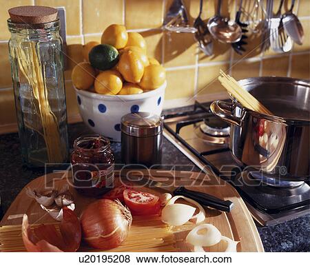 Stock Photo - Close-up of lemons in bowl beside jam jar and onions on chopping board beside steel pan on hob. Fotosearch