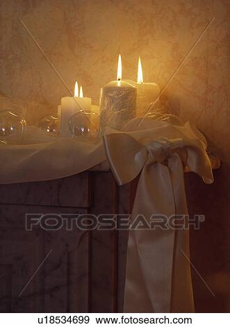 Stock Photo - Close-up of lighted candles on mantelpiece. Fotosearch