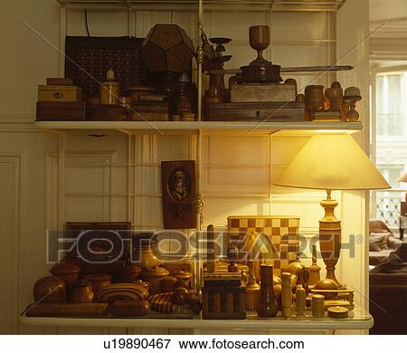 Stock Photo - Close-up of lighted lamp and collection of Treen boxes on shelves. Fotosearch