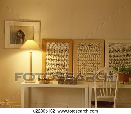Stock Image - Close-up of lighted lamp and shell collage pictures on table. Fotosearch
