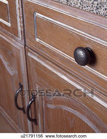 Stock Photograph - Close-up of metal drawer handle on limed drawer of fitted kitchen cupboard. Fotosearch