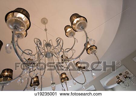 Stock Image - close-up of modern stainless steel chandelier with lampshades and glass teardrops. Fotosearch