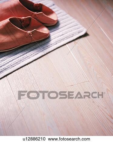 Stock Image - Close-up of Moroccan leather slippers on wooden flooring. Fotosearch