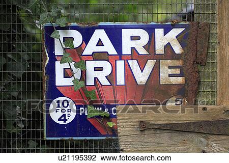 Stock Image - Close up of old metal "Park Drive" advertising poster on fence. Fotosearch