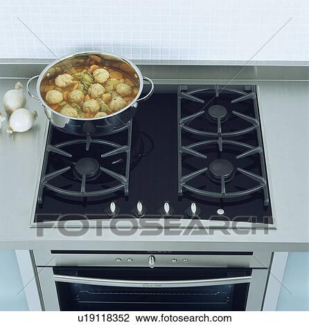 Stock Image - Close-up of pan of food on black gas hob&#13; &#10; &#13; &#10; &#13; &#10; &#13; &#10; &#13; &#10; &#13; &#10;. Fotosearch