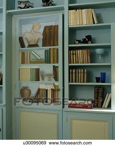 Stock Photo - Close-up of pastel blue bookshelves with trompe l'oiel door. Fotosearch