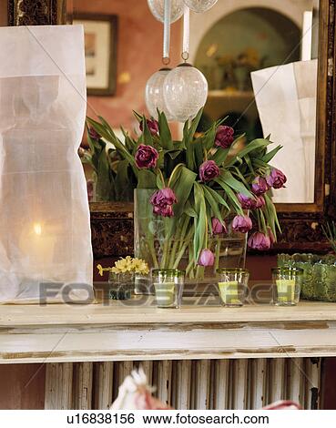 Stock Photograph - Close-up of pink tulips and lighted mdoern lamp on shelf. Fotosearch