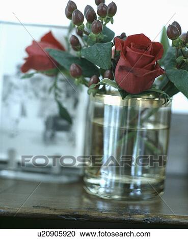Stock Image - Close-up of red roses in glass vase. Fotosearch