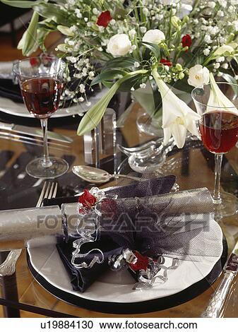 Stock Image - Close-up of silver cracker and gift-box decorated with black tulle and silver ribbon on white plate. Fotosearch