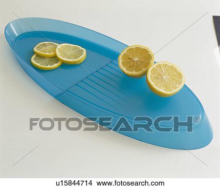 Picture - Close-up of sliced lemons on oval blue plastic tray. Fotosearch