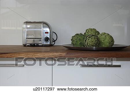 Stock Photo - Close up of stainless steel Dualit toaster on worktop with artichokes on dish. Fotosearch