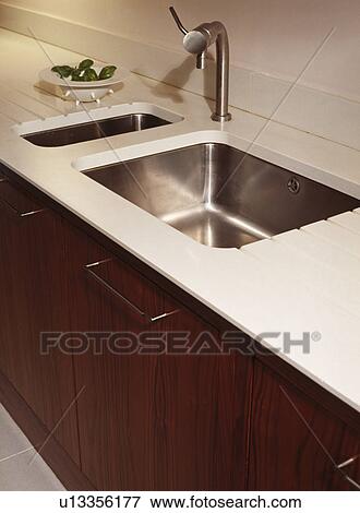 Close-up of stainless steel mixer tap and underset double steel sinks in modern white kitchen worktop View Large Photo Image Stock Photo - Close-up of stainless steel mixer tap and underset double steel sinks in modern white kitchen worktop. Fotosearch