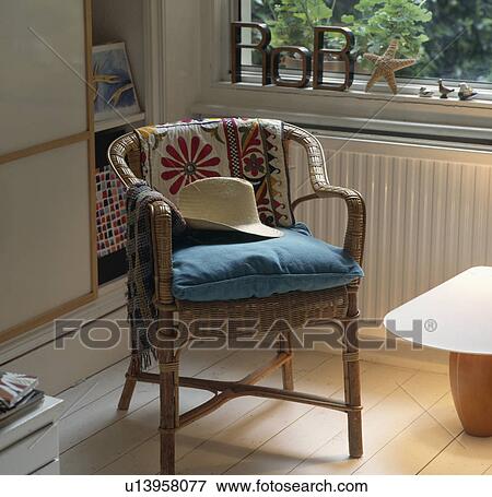 Close-up of straw hat and blue cushion on wicker chair with embroidered fabric throw in corner of bedroom View Large Photo Image Stock Photo - Close-up of straw hat and blue cushion on wicker chair with embroidered fabric throw in corner of bedroom. Fotosearch