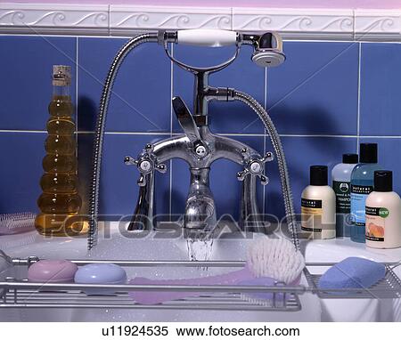 Stock Photography - Closeup bath taps with shower attachment against blue tiles.. Fotosearch