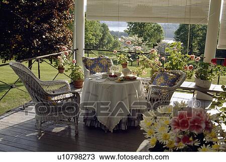 Stock Image - Cloth on table on veranda in country garden in summer. Fotosearch