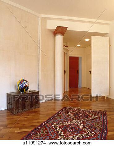 Picture - Colourful ceramic vase on carved wooden chest in apartment hall with vertical radiator and pillar roof support. Fotosearch