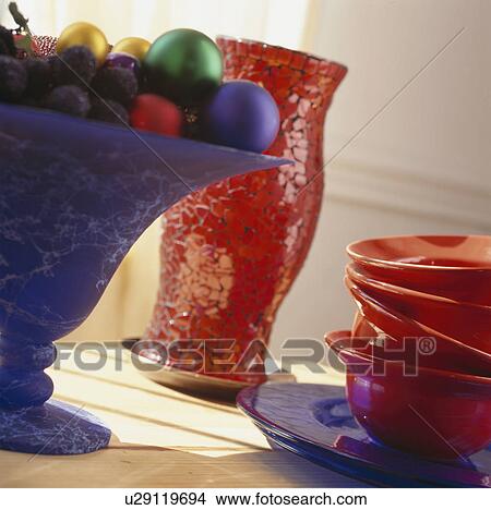 Picture - Colourful Christmas baubles in blue glass stemmed bowl with red bowls and red glass hurricane lantern. Fotosearch