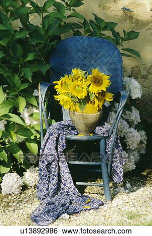 Stock Photograph - Colourful flowers and cloth on table in country garden in summer. Fotosearch