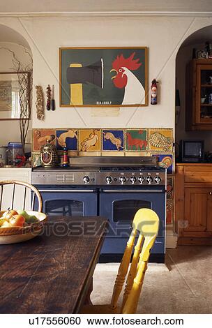 Colourful tiles above blue range oven in country kitchen with old wooden table and chairs View Large Photo Image Stock Image - Colourful tiles above blue range oven in country kitchen with old wooden table and chairs. Fotosearch
