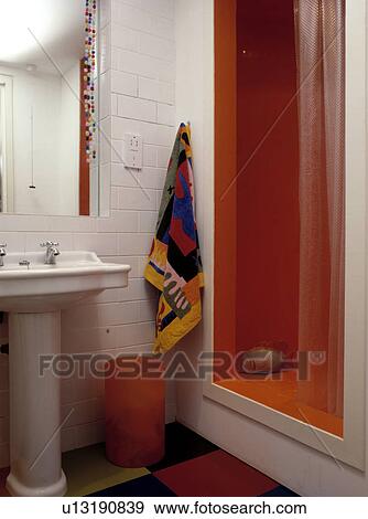 Colourful towel on white tiled wall beside orange shower cabinet in modern bathroom View Large Photo Image Stock Photo - Colourful towel on white tiled wall beside orange shower cabinet in modern bathroom. Fotosearch