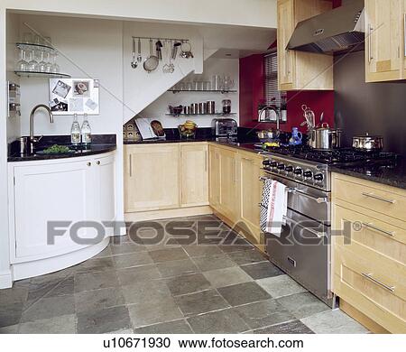 Corner sink and pale wood fitted cupboards in modern kitchen with stainless steel oven and slate floor tiles View Large Photo Image Stock Image - Corner sink and pale wood fitted cupboards in modern kitchen with stainless steel oven and slate floor tiles. Fotosearch