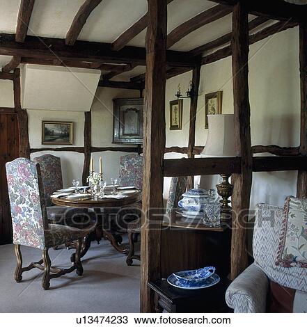 Stock Image - Cottage dining room with exposed beams on walls and ceiling. Fotosearch