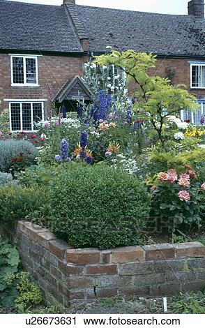 Stock Image - Cottage with low brick wall in front garden in summer. Fotosearch