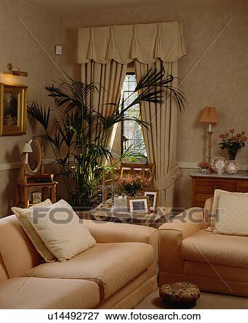 Stock Photo - Cream curtains and sofas in traditional living room. Fotosearch