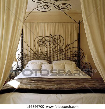 Cream cushions and drapes with faux fur throw on wrought iron bed designed by Mark Brazier-Jones in cream bedroom View Large Photo Image Stock Image - Cream cushions and drapes with faux fur throw on wrought iron bed designed by Mark Brazier-Jones in cream bedroom. Fotosearch