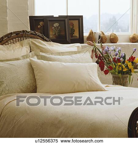 Stock Photography - Cream pillows and bedcover on bed in front of window. Fotosearch