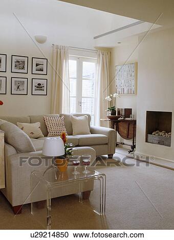 Stock Image - Cream sofas and carpet in small town lviing room. Fotosearch