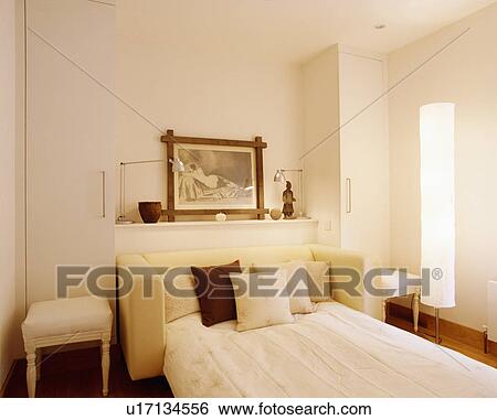 Cushions and linen on sofabed in neutral modern livingroom guestroom with cylinder lamp View Large Photo Image Stock Photograph - Cushions and linen on sofabed in neutral modern livingroom guestroom with cylinder lamp. Fotosearch