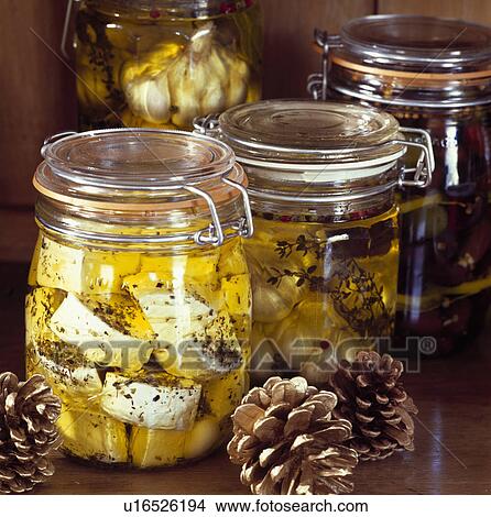 Picture - Detail of glass preserving jars filled with cheese, garlic and vegetables in oil . Fotosearch