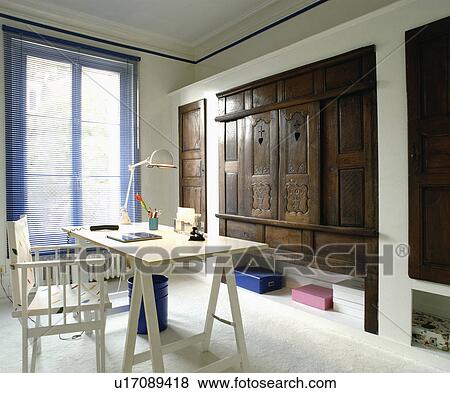 Director's chair and modern trestle table in home office with old carved wooden doors on cupboard View Large Photo Image Stock Photo - Director's chair and modern trestle table in home office with old carved wooden doors on cupboard. Fotosearch