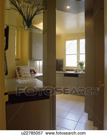 Doorway with view of white floor tiles in modern yellow kitchen with grey fitted cupboards View Large Photo Image Stock Photo - Doorway with view of white floor tiles in modern yellow kitchen with grey fitted cupboards. Fotosearch