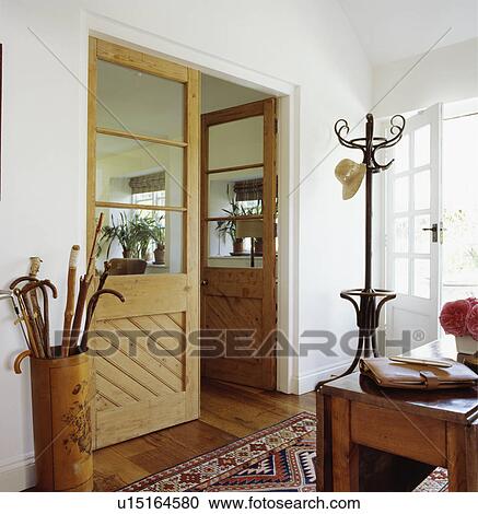 Stock Image - Double half-glazed doors in white hall with bentwood hatstand and walking sticks in cylindrical holder. Fotosearch