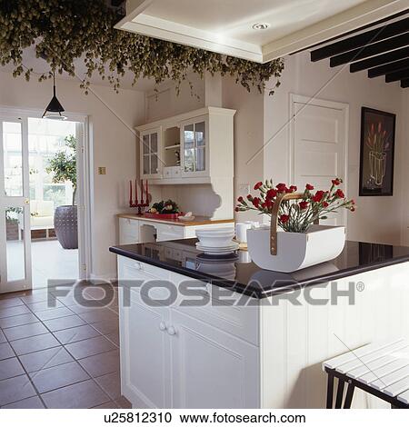 Dried hops on beams above granite-topped island unit in modern white kitchen with tiled floor View Large Photo Image Stock Image - Dried hops on beams above granite-topped island unit in modern white kitchen with tiled floor. Fotosearch