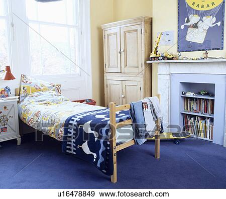Stock Photo - Duck-patterned blue rug on pine bed in child's bedroom with pine cupboard and fireplace with shelves in the grate. Fotosearch