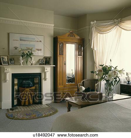 Edwardian wardrobe with mirrored door in bedroom with white swagged curtains and white fireplace View Large Photo Image Stock Photo - Edwardian wardrobe with mirrored door in bedroom with white swagged curtains and white fireplace. Fotosearch